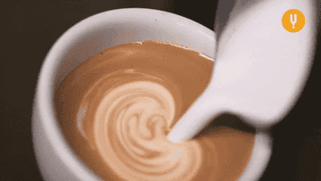 Cup of espresso with sumptuous stream of cream being poured in with a twirl
