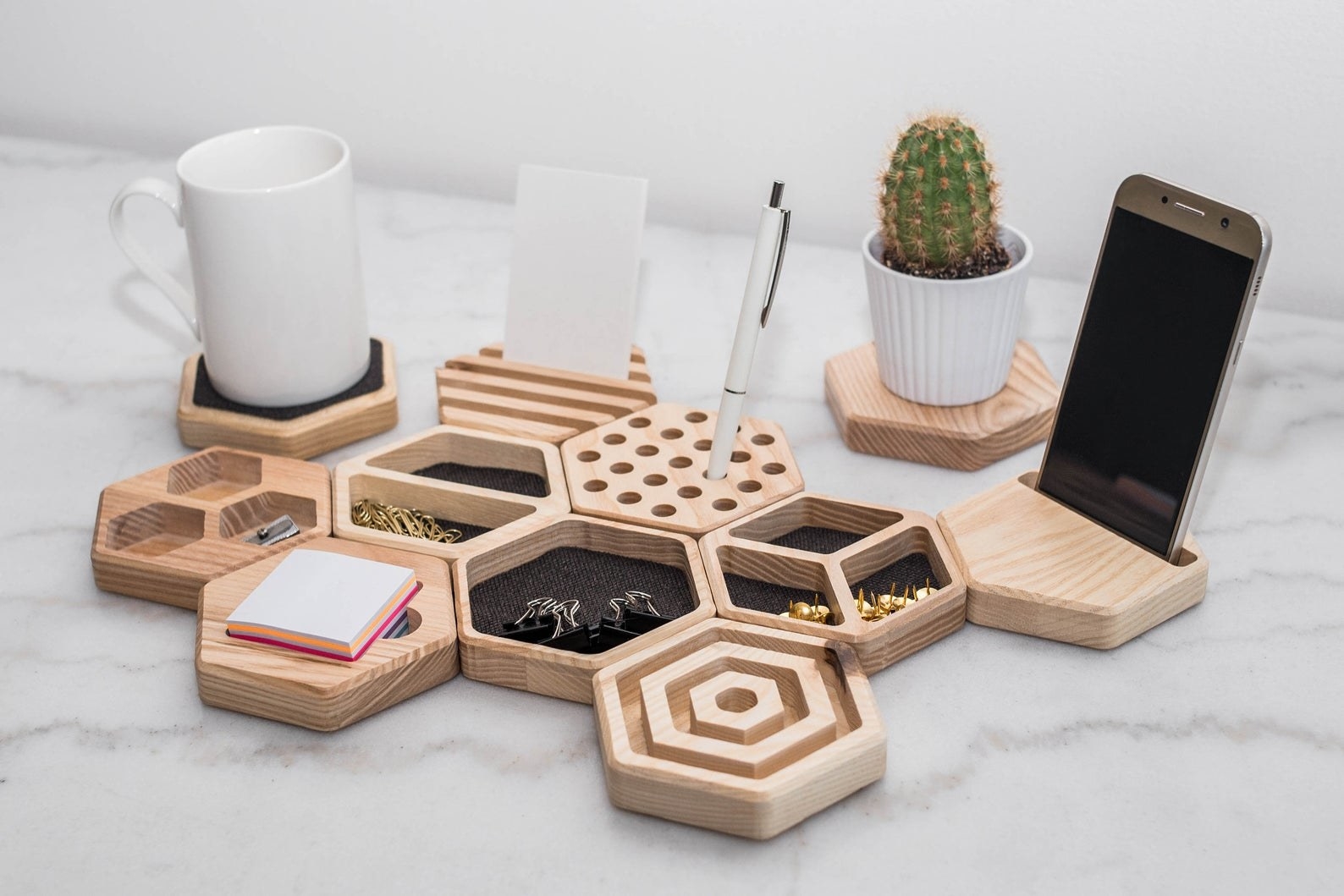 many hexagonal desk organizers holding office supplies, a phone, and pens