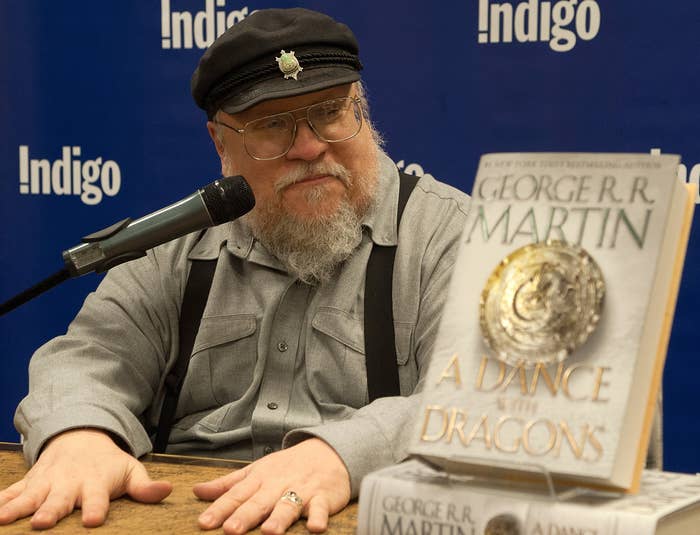 George sits next to a copy of A Dance With Dragons at a book signing