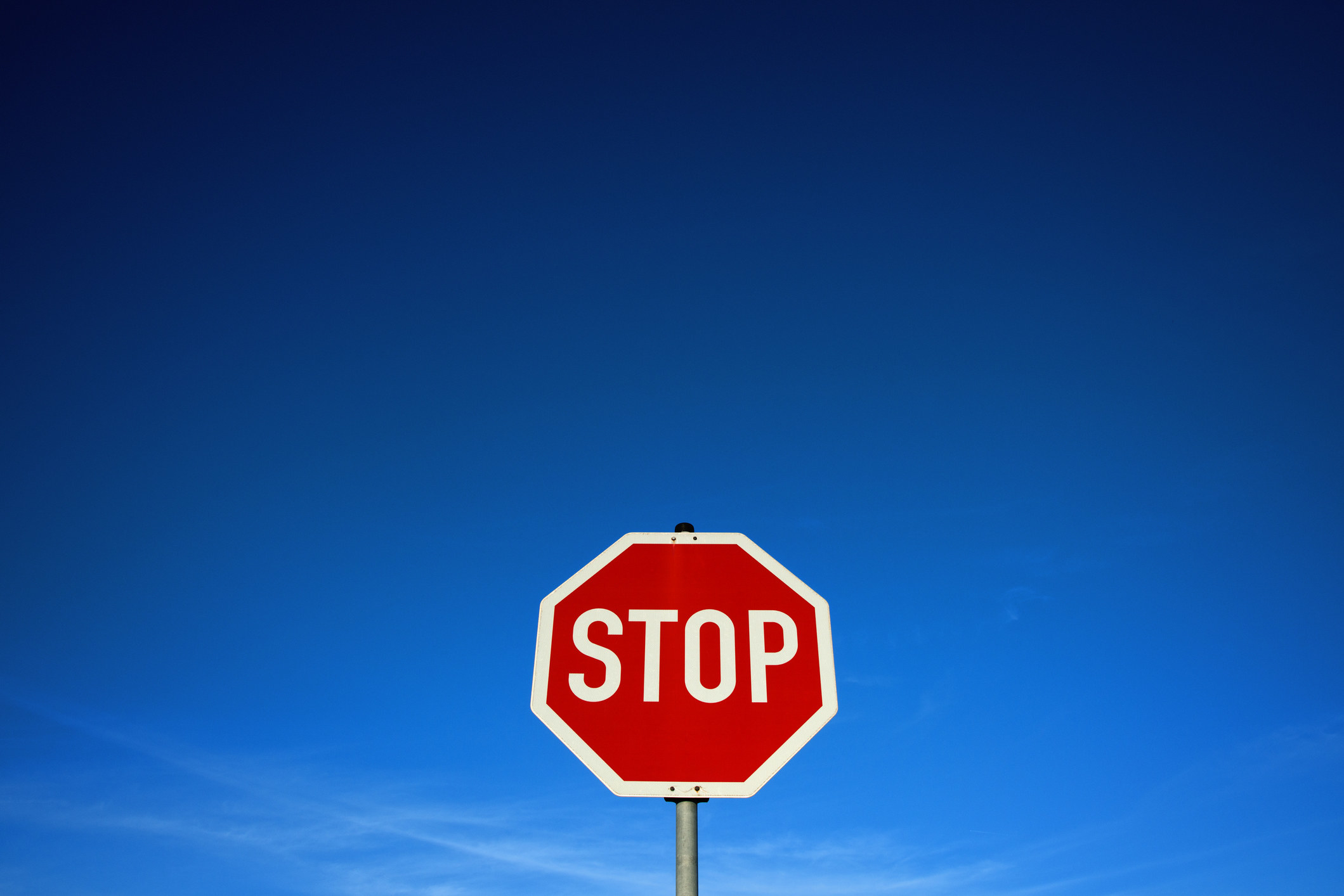 A stop sign at the bottom of the frame with a big empty sky behind it