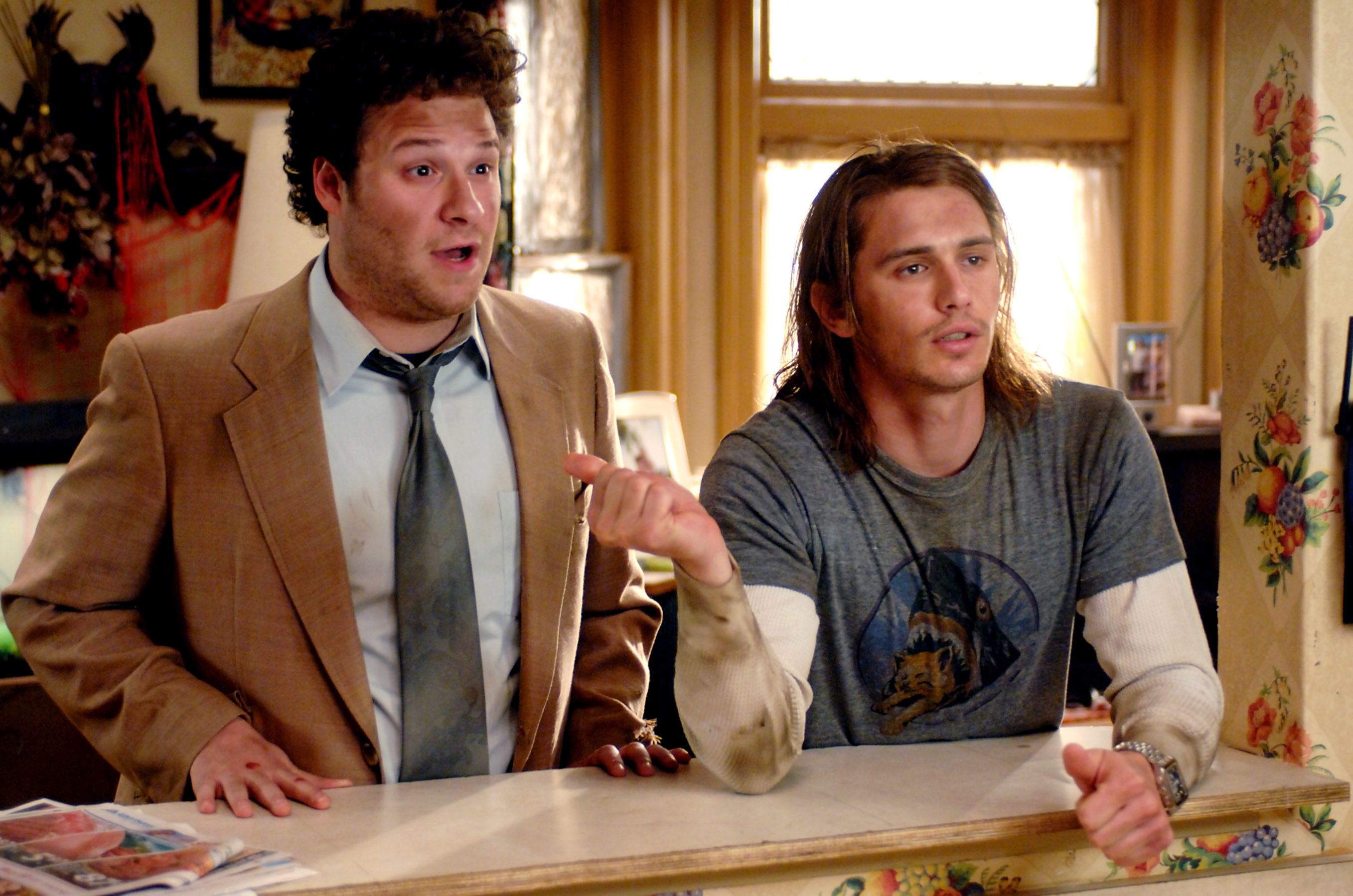 Seth Rogen and James Franco look disheveled as they lean on a counter