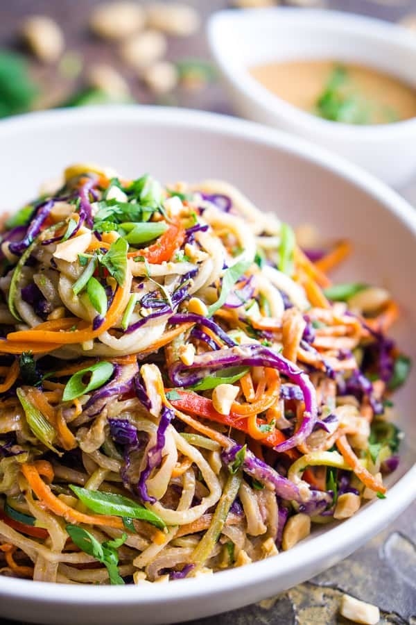 Colorful shredded vegetables and noodles piled into a white bowl