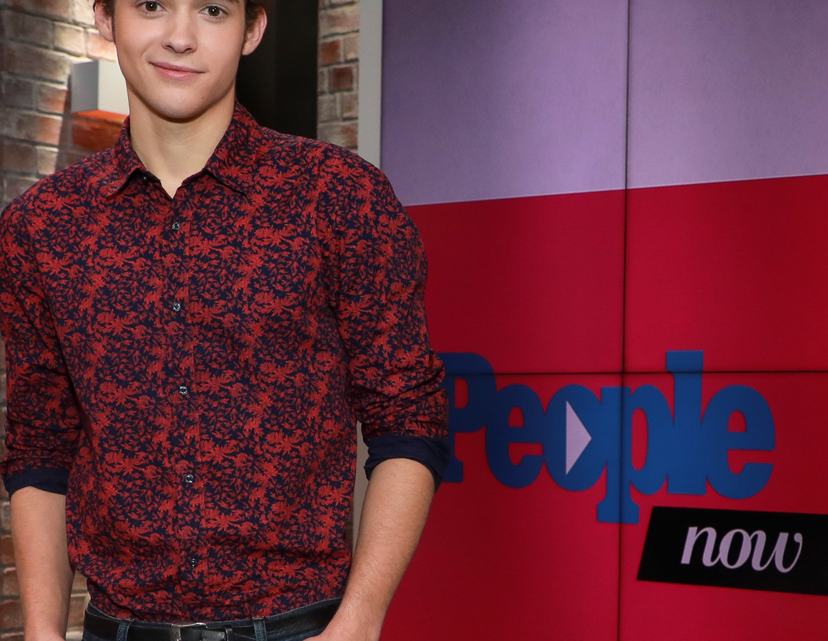 Joshua wears a red and blue floral patterned button down