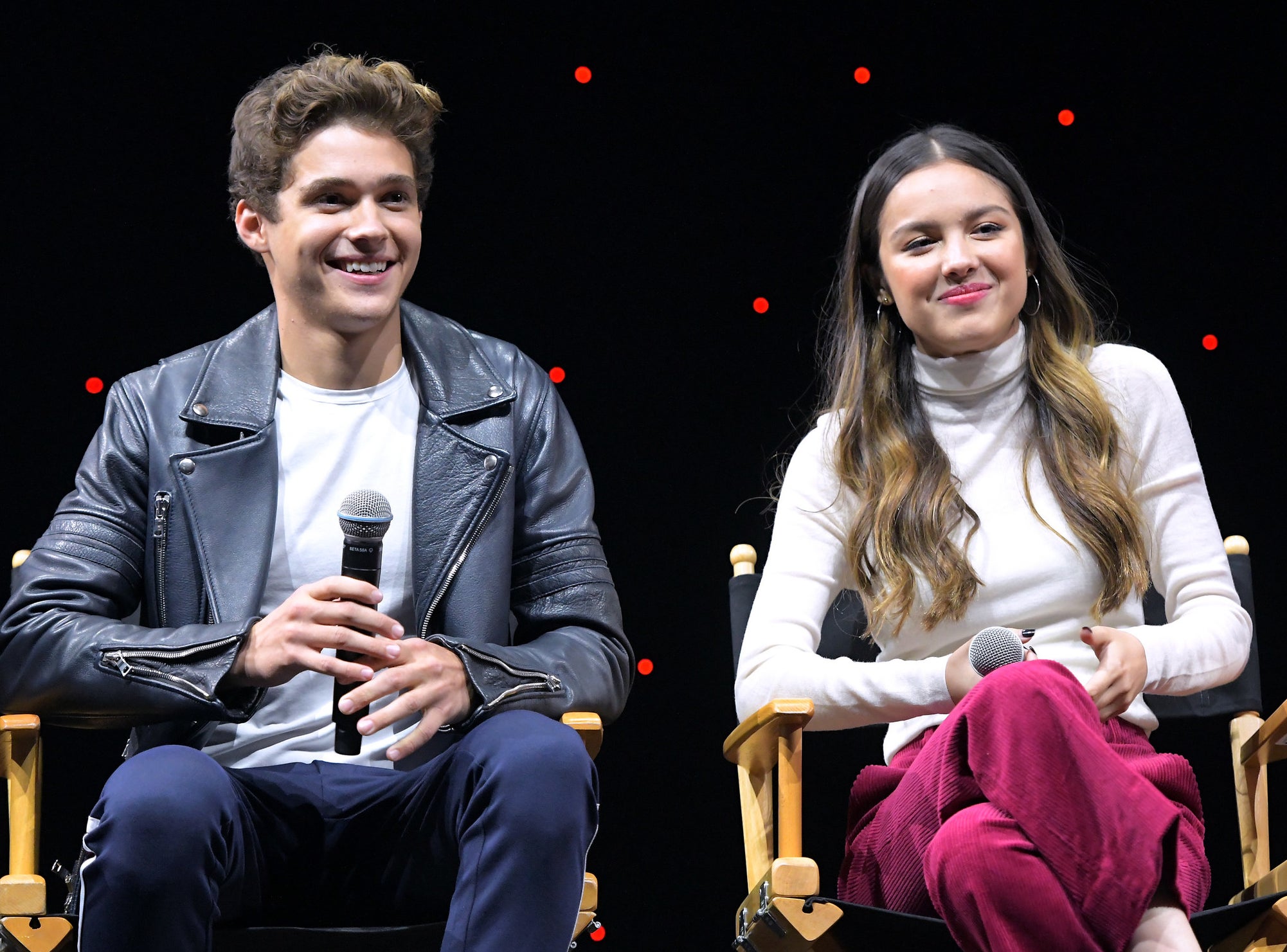 Joshua and Olivia smile while speaking onstage