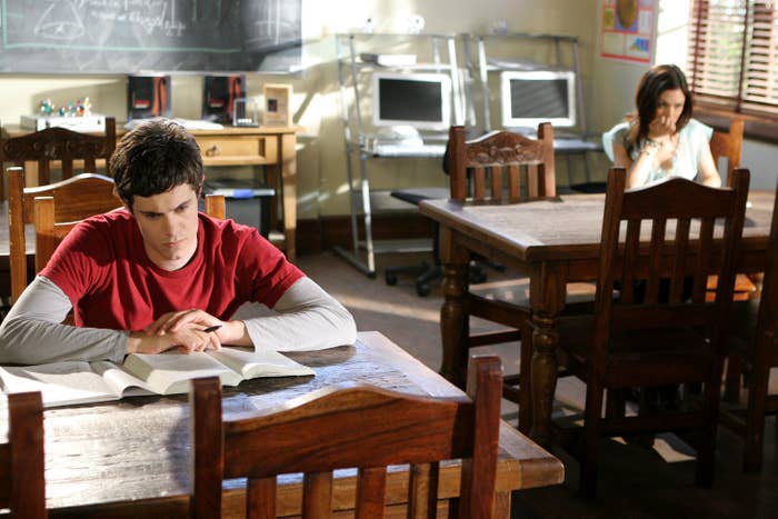 Brody sits at a table in front of an open book with a frown on his face