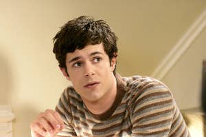Adam Brody looks up while wearing a striped t-shirt