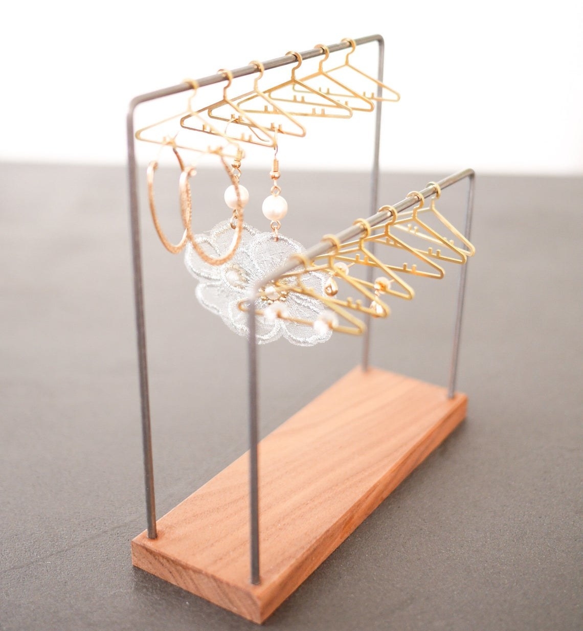 two bars with small gold hangers and earrings hanging from them