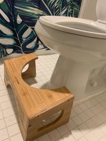 reviewer image of the bamboo squatty potty in front of a toilet