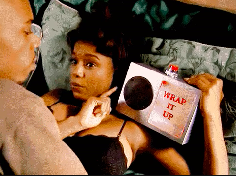 A woman holding up a timer that says &quot;wrap it up&quot; during sex