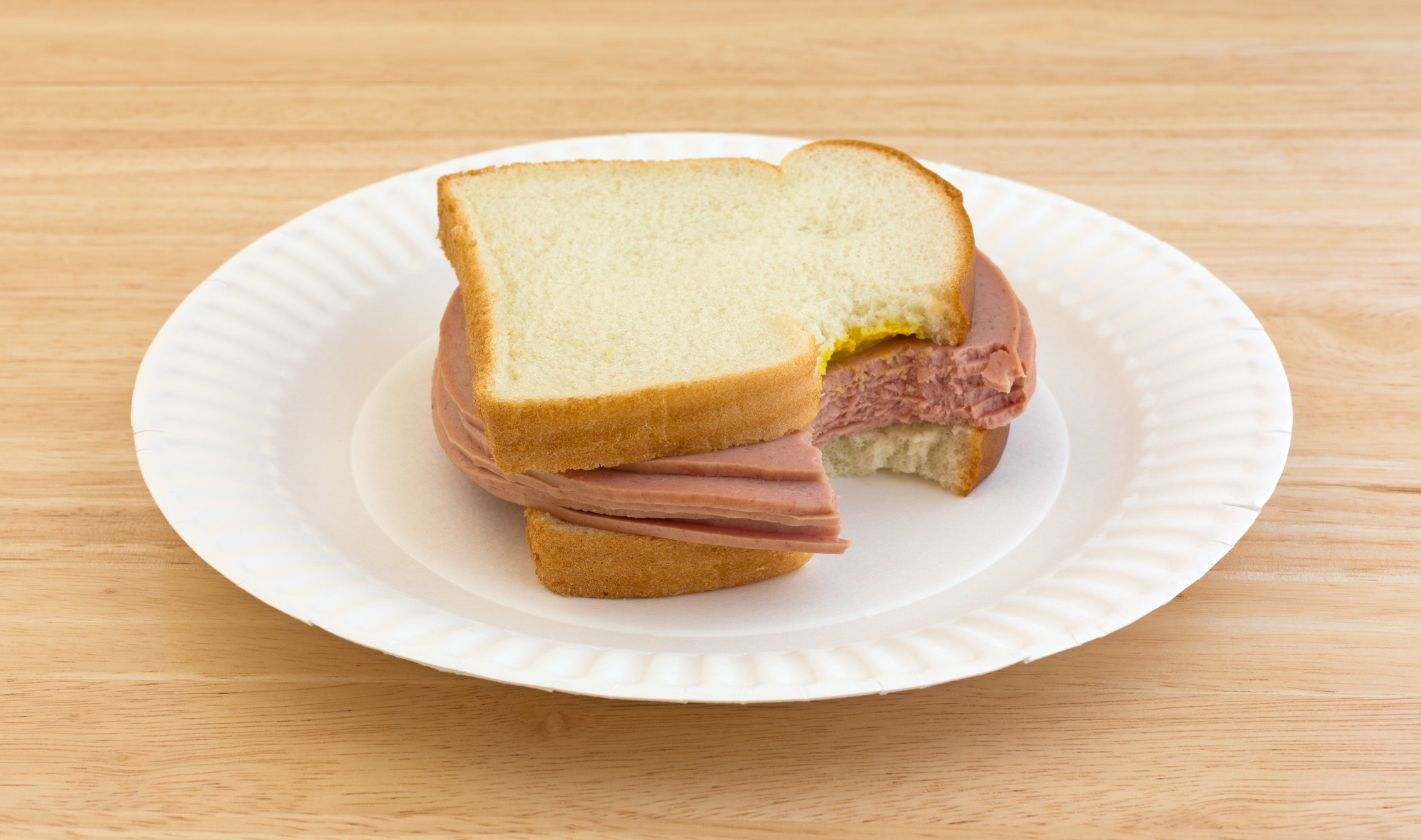 A bologna sandwich on a paper plate
