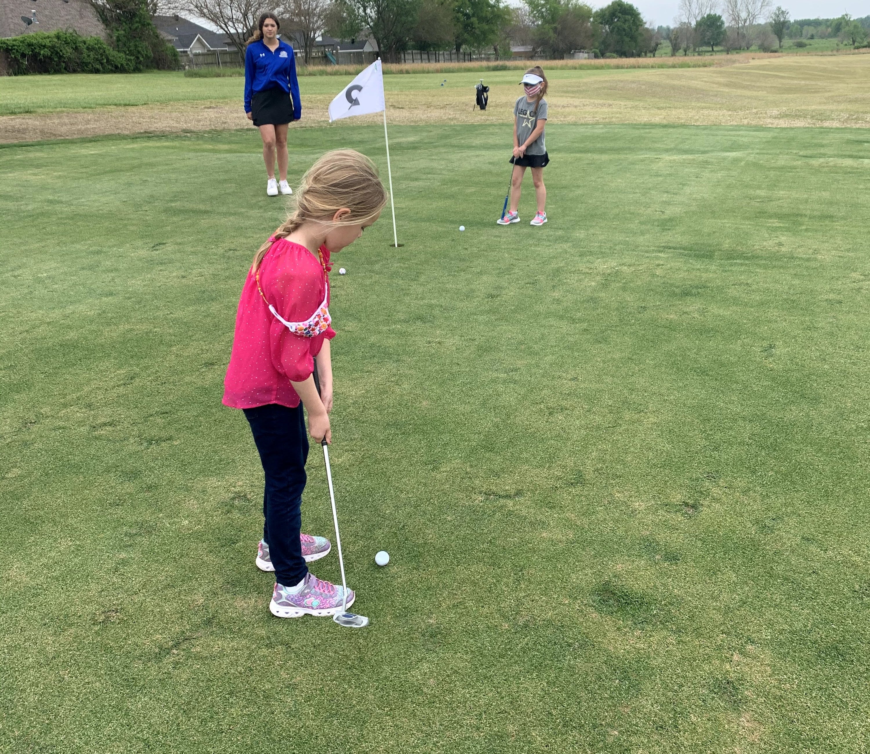 A little girl playing golf