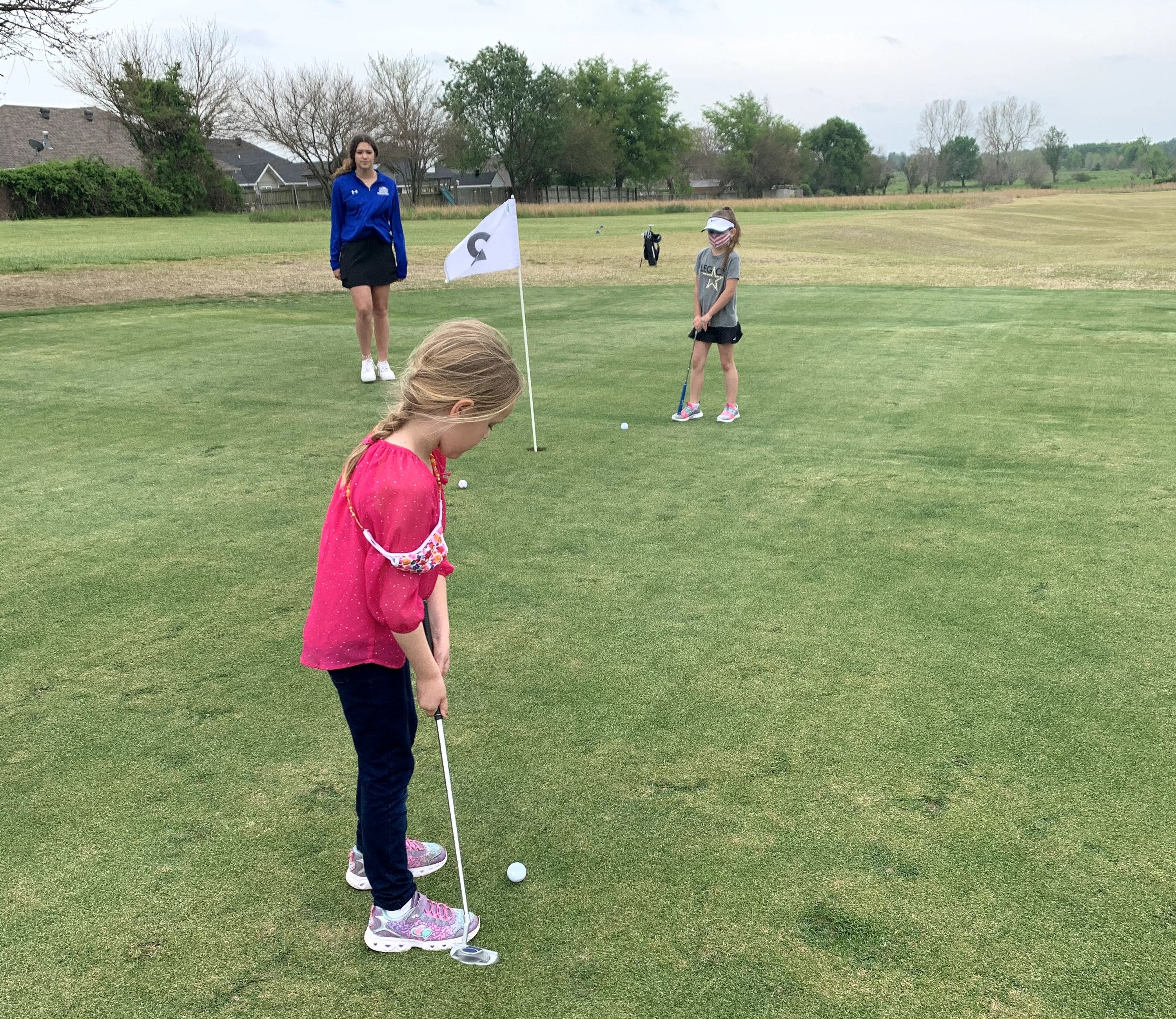 A little girl playing golf
