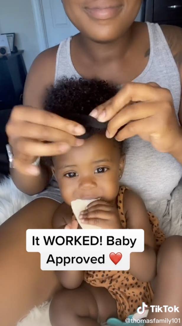 Mom putting headband on baby, who's eating a cookie, with the caption, "It worked! Baby approved"