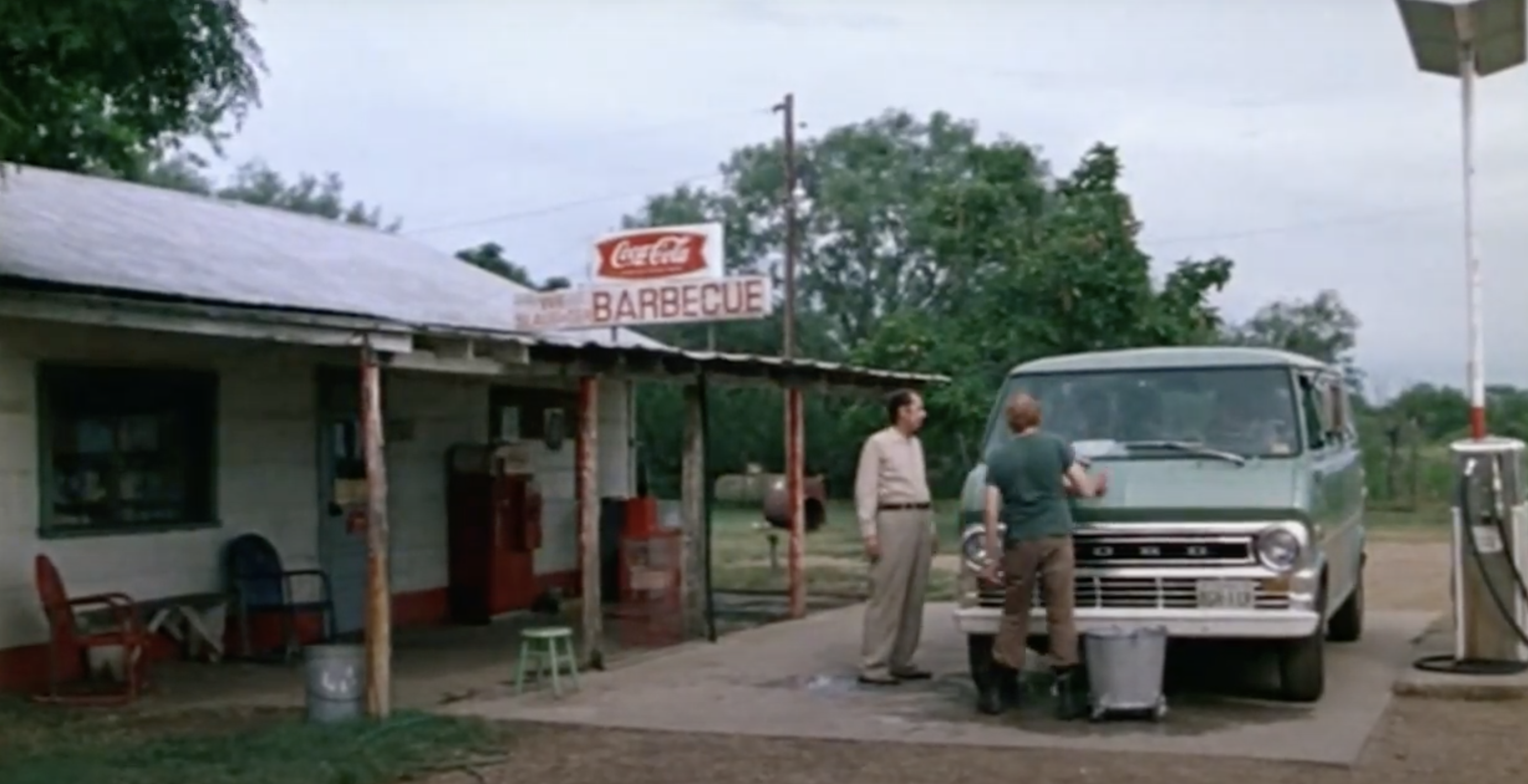 two men pumping gas into a van in front of the iconic gas station