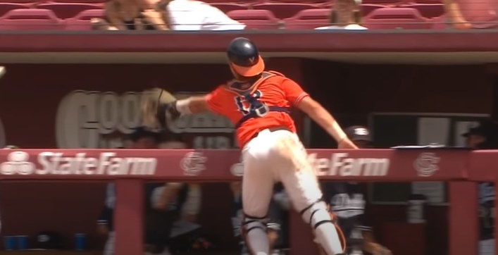 Baseball catcher catches the ball while leaning into the dugout