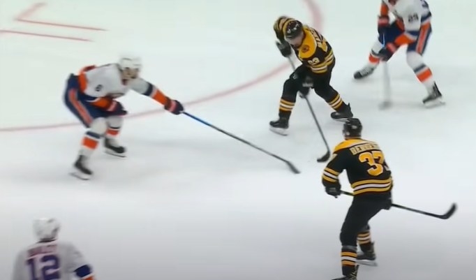 Brad Marchand handles the puck between opponents on the ice
