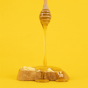 Side view of honey dripping from a honey dipper onto a thick piece of toast with banana