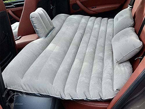 The car mattress inflated and set up in the back seat of a car.