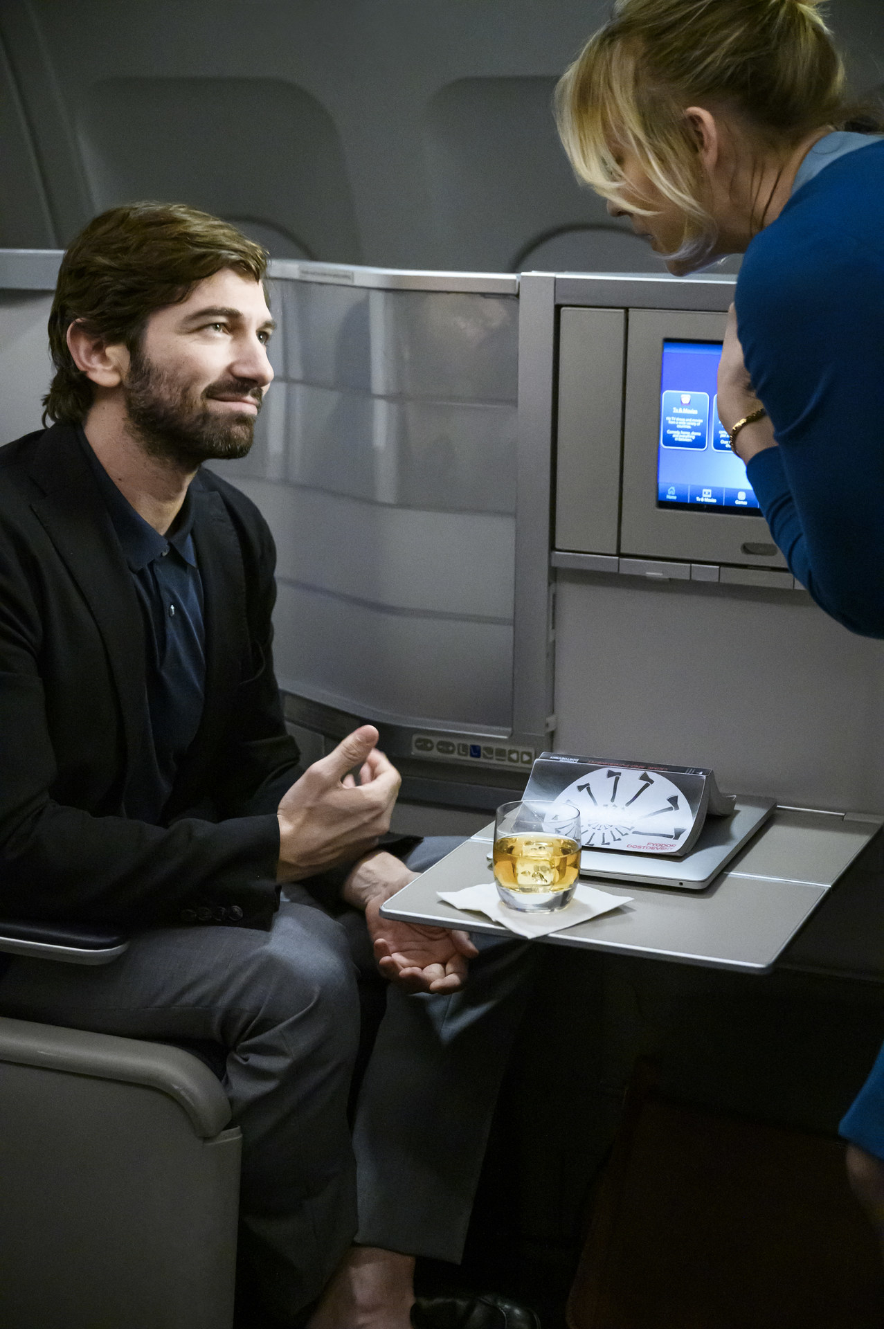 Kaley attending to Michiel in an airplane in a scene from The Flight Attendant