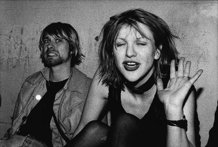 Black-and-white photo of Kurt and Courtney sitting against a wall