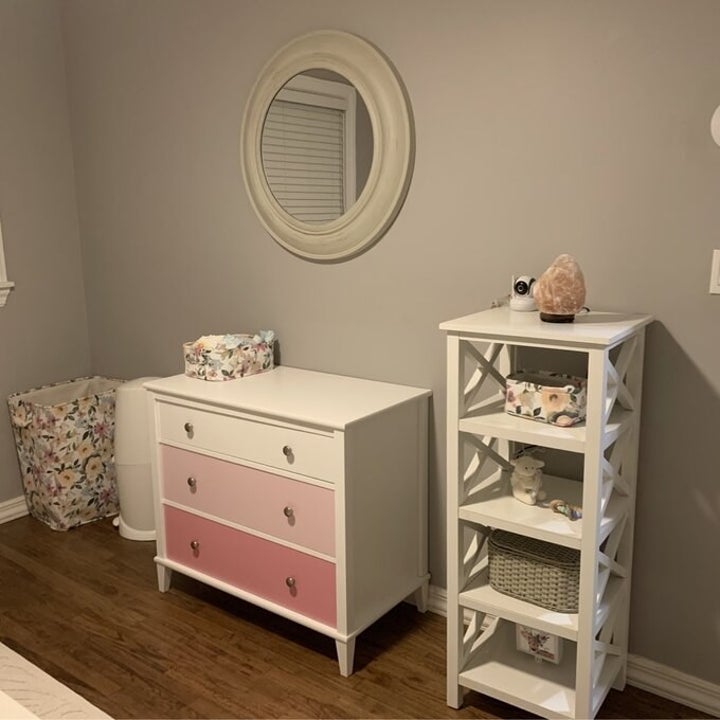 reviewer photo of the changing table in pink and white in a nursery