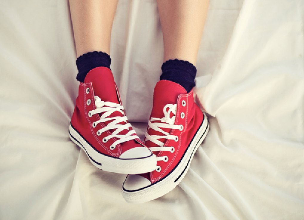 Someone wearing sneakers in bed