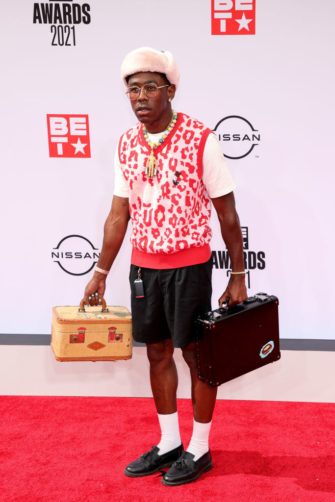 Tyler, the Creator attends the BET Awards 2021 carrying a suitcase and wearing a sweater vest and shorts