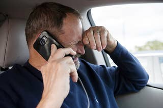 A man cries on the phone in a car after sharing some bad news, holds his hand to his head