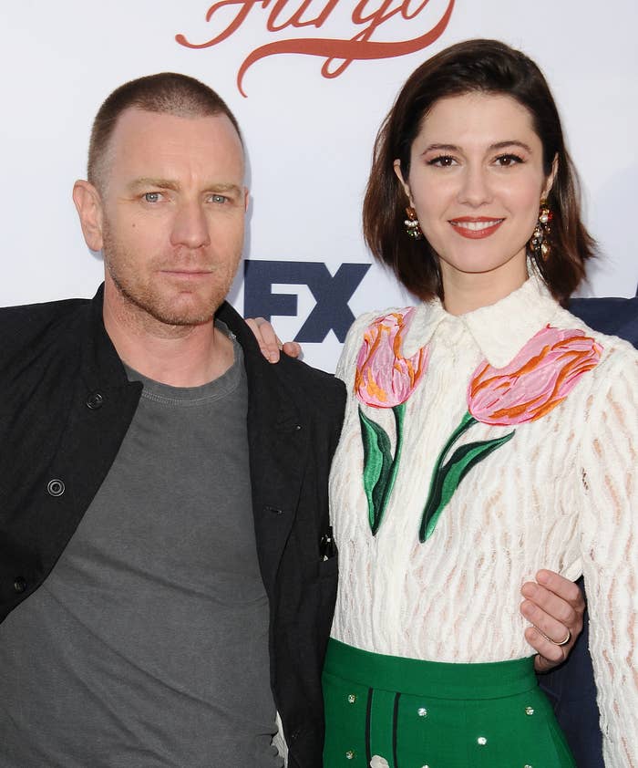 Ewan McGregor, in a black button-down and gray t-shirt, with his arm around Mary Elizabeth Winstead, in a white collared blouse with tulip patterns