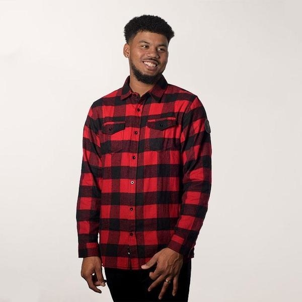 A photo of a man posing in a plaid sweater.
