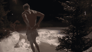 A GIF of a shirtless man doing snow angels.