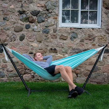 a model lounges on a turquoise vivere hammock