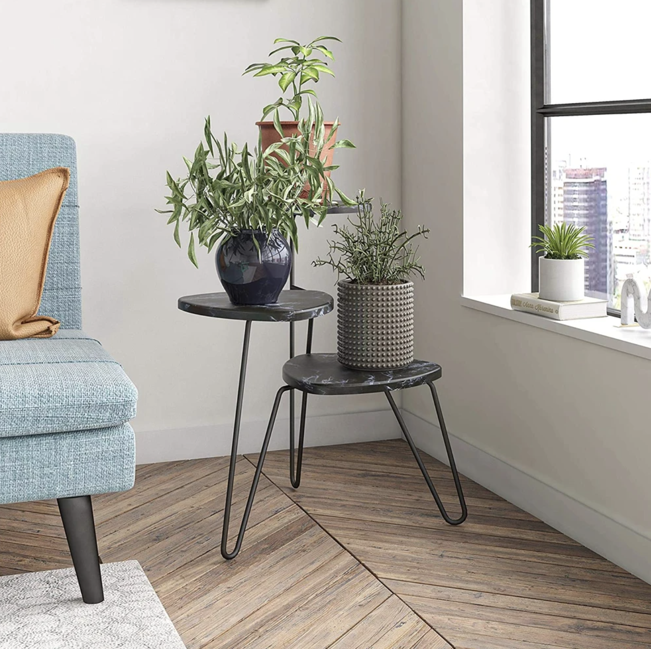 The black marble and metal plant stand displays three plants