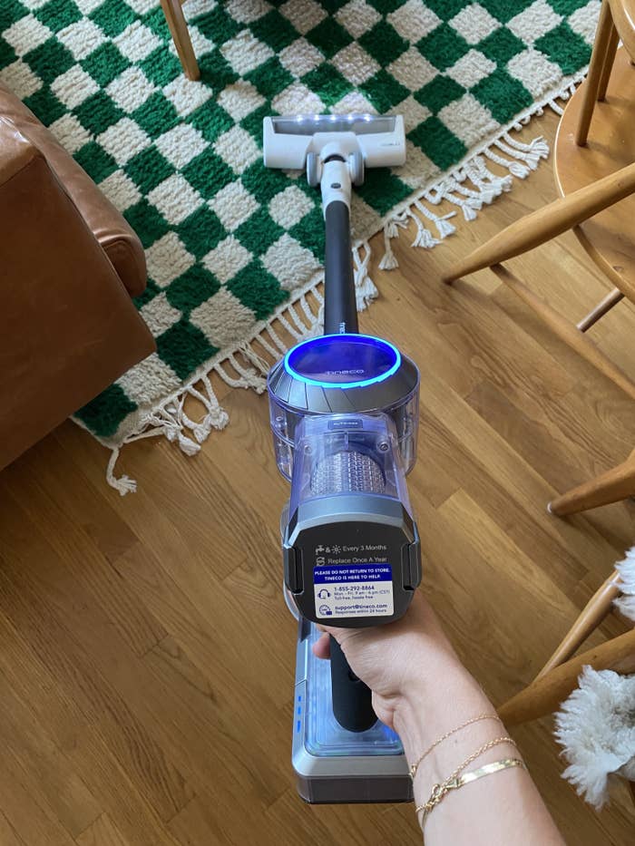 the vacuum being used on a checkered green and white rug