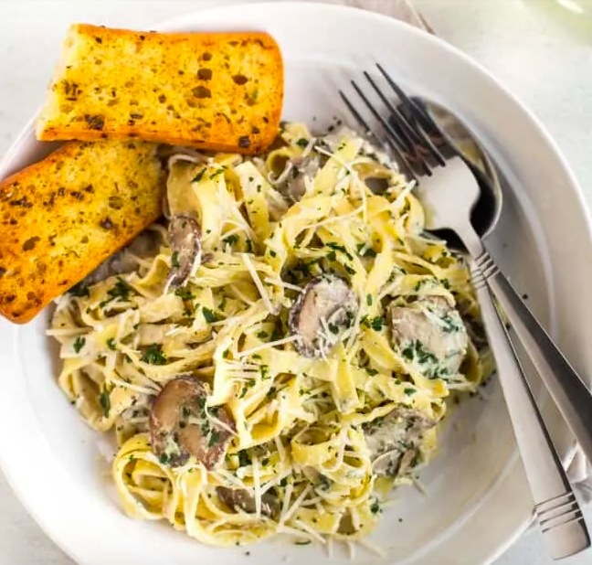 Creamy tagliatelle noodles tossed with garlic mushrooms and served with two small pieces of garlic bread.