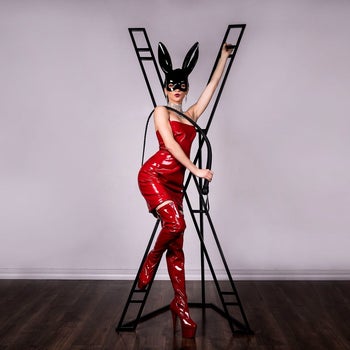 Model in red latex posing with black freestanding cross