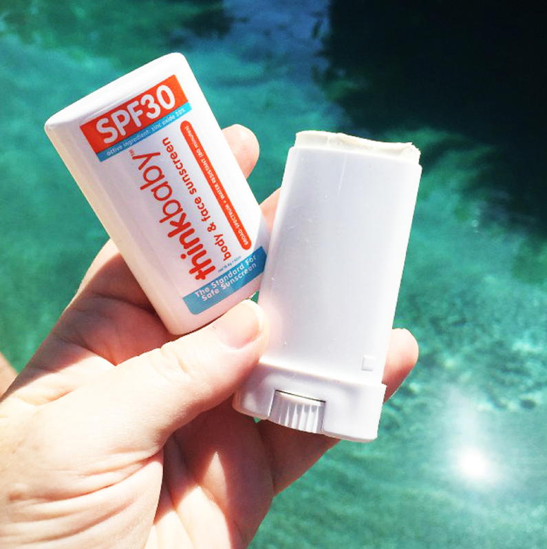 a hand holding the tube of sunscreen which is designed like deodorant