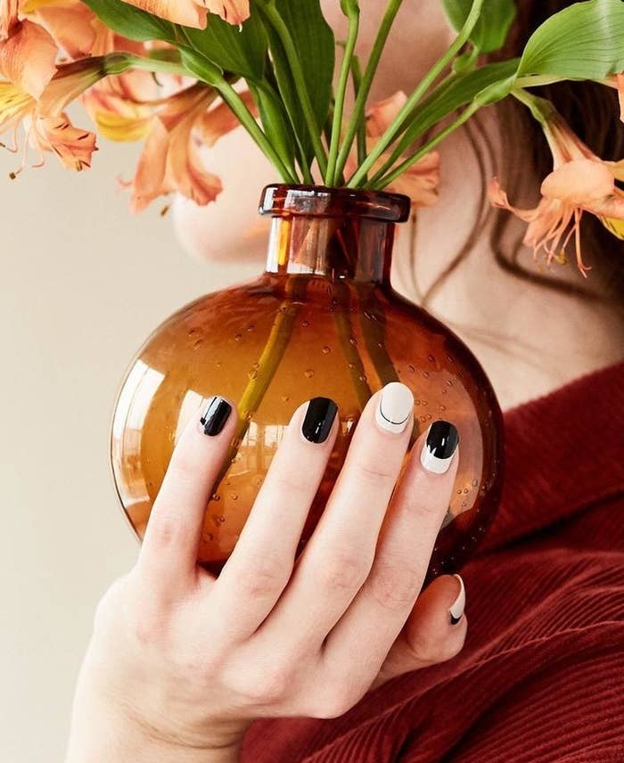 model holding a flower pot and showing black and white nails