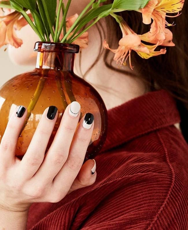 model holding a flower pot and showing black and white minimalist designed nails