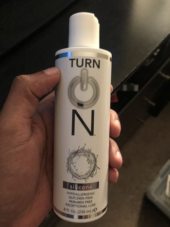 Reviewer holding white bottle of lubricant with pour top