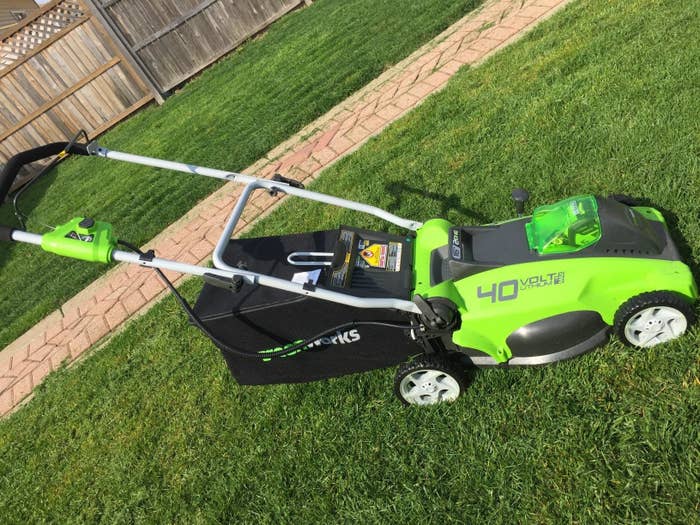 A reviewer&#x27;s photo of the bright green and black lawn mower