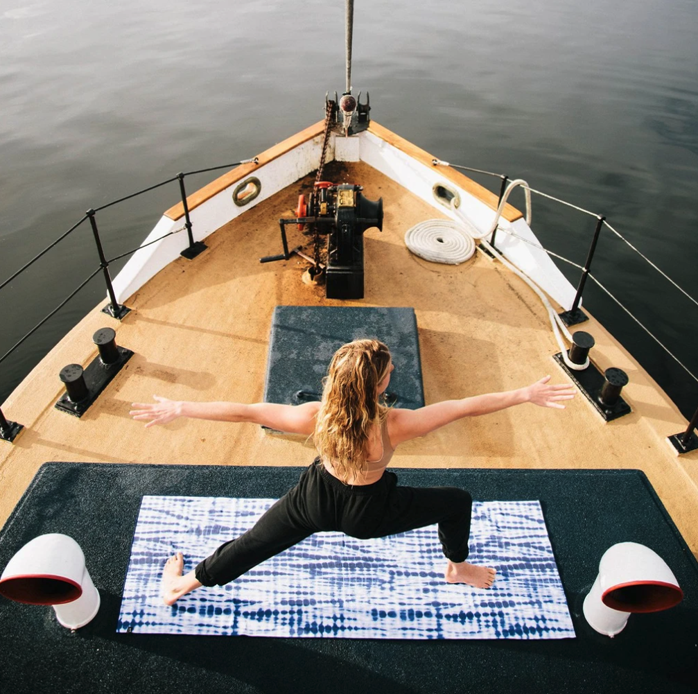 A person doing yoga on the mat on a boat