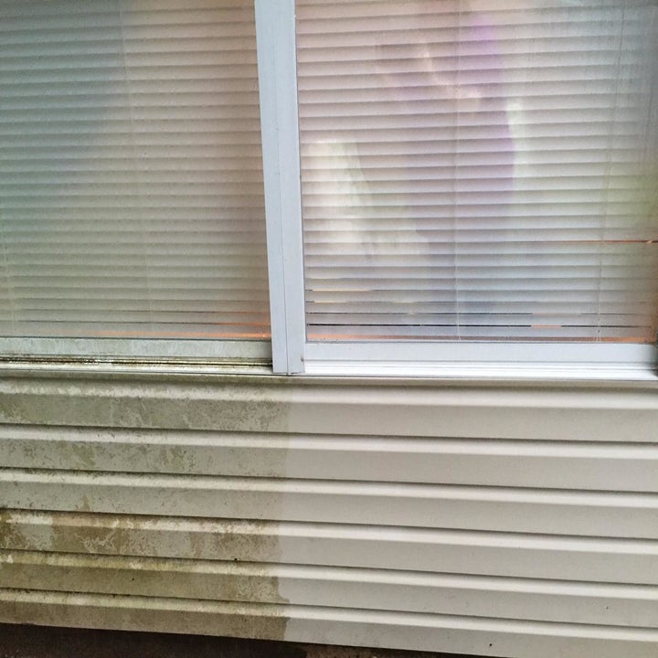 Reviewer's picture of their house with one half still dirty and one half now clean thanks to the pressure washer