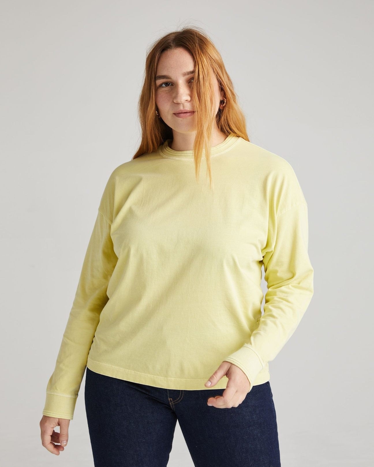 model wearing the long sleeve tee in yellow with dark denim jeans