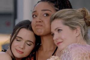 three girls in their twenties holding each other while one of them cries
