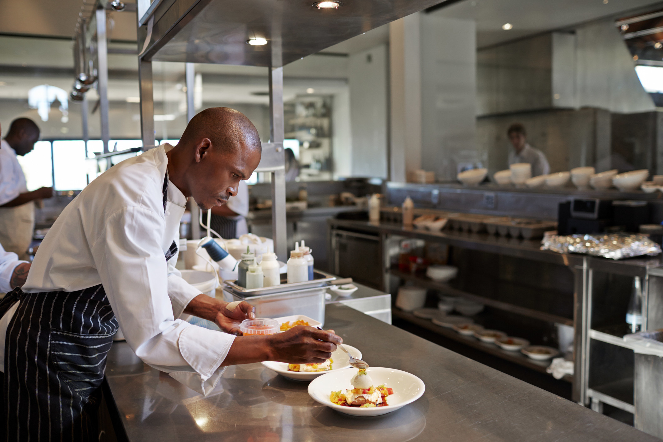 A chef sprucing up a dish in the kitchen