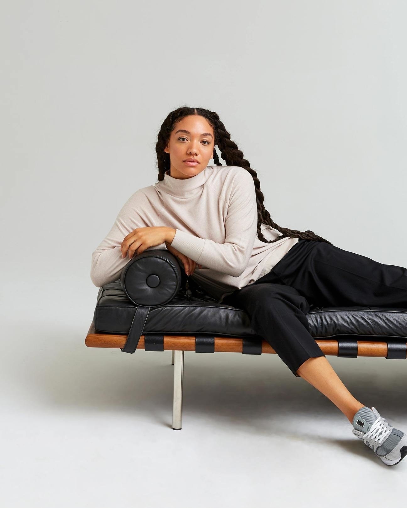 model wearing the sweater in cream with blank pants lounging on a couch