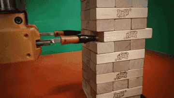 A robot/machine with two small arms meticulously playing Jenga