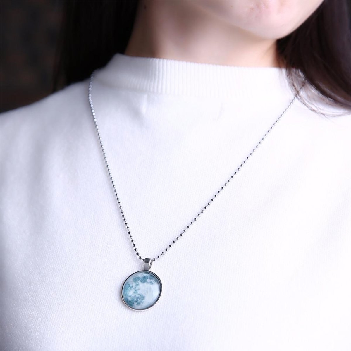 A woman wearing a moon pendant necklace.