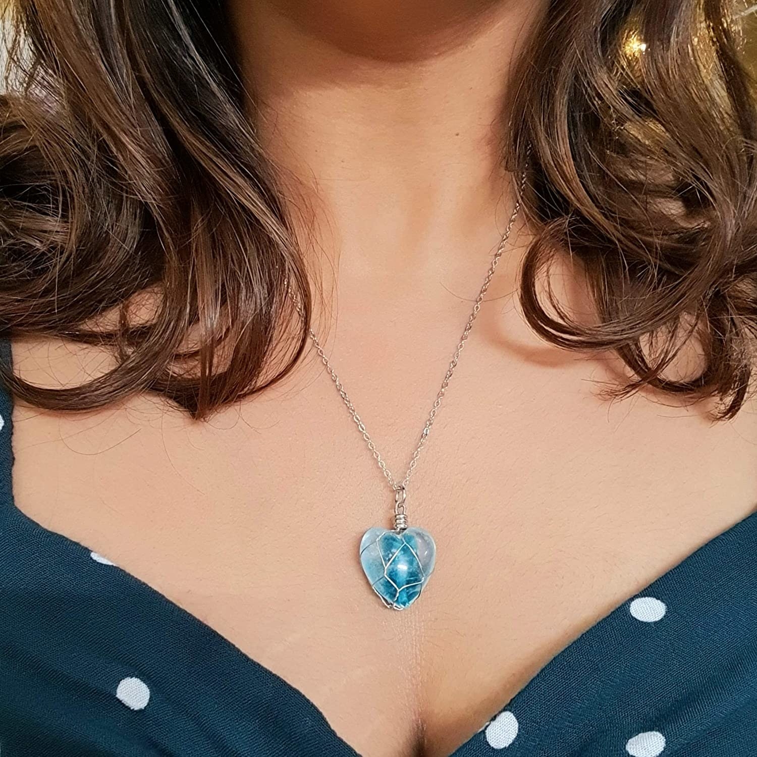 A woman wearing a heart shaped blue pendant.